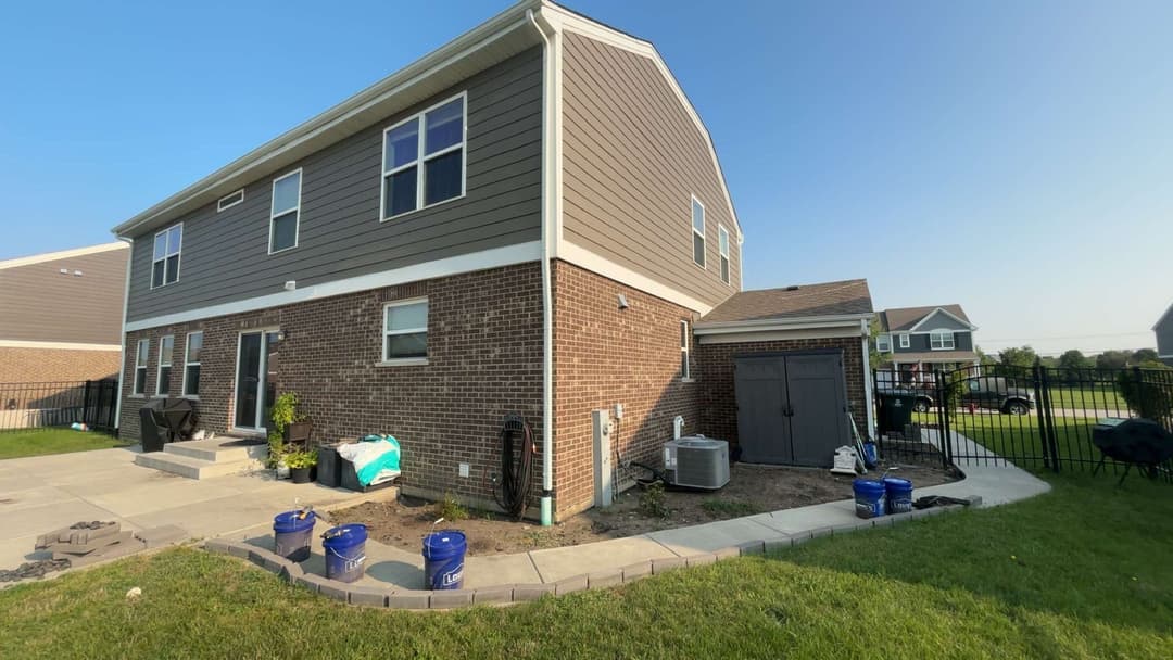 Newly built two-story home exterior with brick and siding, featuring a landscaped yard.