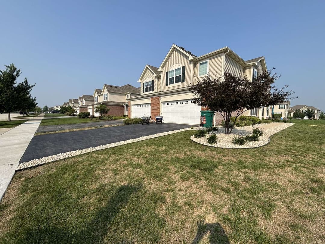 Modern suburban home with manicured lawn and driveway, clear blue sky in the background.