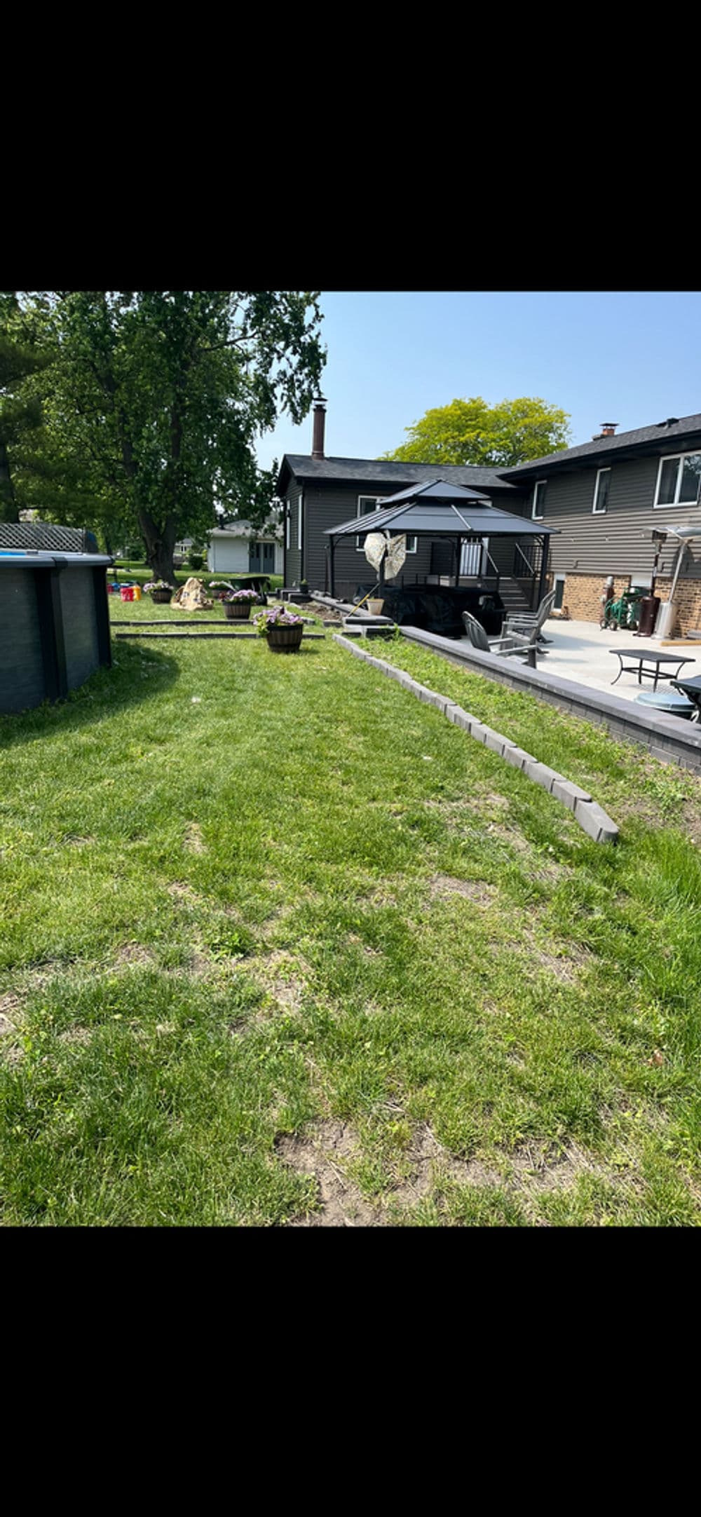 Lush green backyard with picnic area, shed, and a view of the house and parked RV.