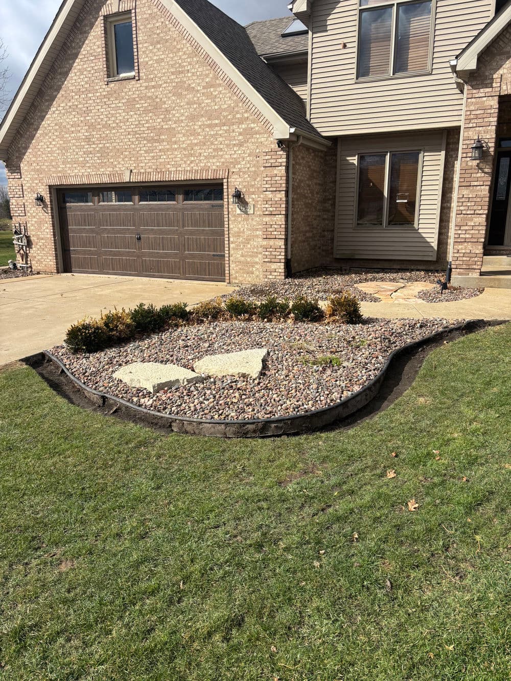 front yard landscaping with stone border and decorative gravel near brick house