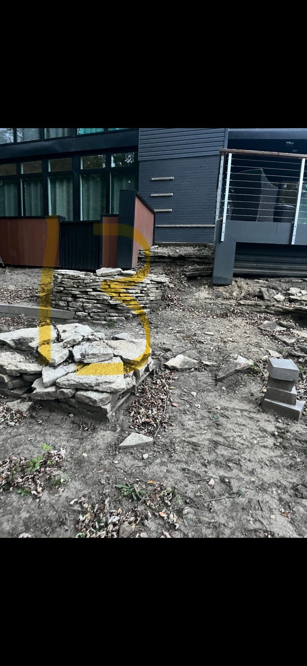 Stone landscaping near modern building with exposed foundation and construction materials.
